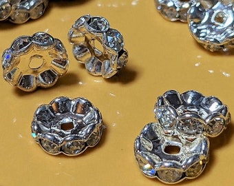 May include: Silver-toned metal bead with a clear rhinestone border. The bead has a hole in the center for stringing.