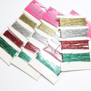 May include: Assortment of metallic craft cords in gold, silver, red, and green. The cords are packaged in clear plastic bags with white labels that read "Create & Craft D.I.Y."