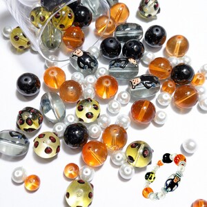 May include: A variety of colorful glass beads, including orange, brown, black, white, and clear. Some beads have a polka dot pattern, while others feature a monkey design. There is also a bracelet with a monkey charm.