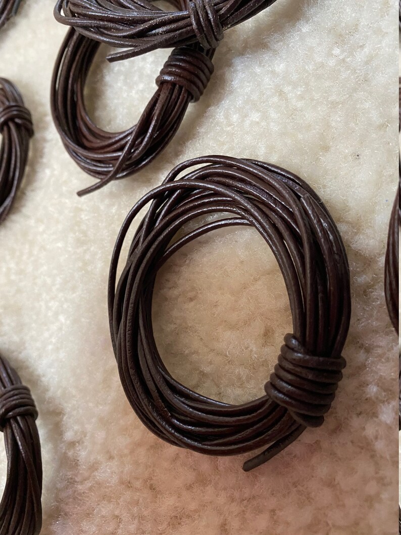 May include: A close-up of a spool of brown leather cord. The cord is wound tightly and is ready to be used for crafting projects.