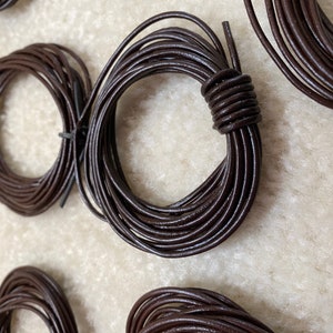 May include: Close-up of five spools of brown leather cord. The cord is wound into neat circles and is ready for crafting projects.