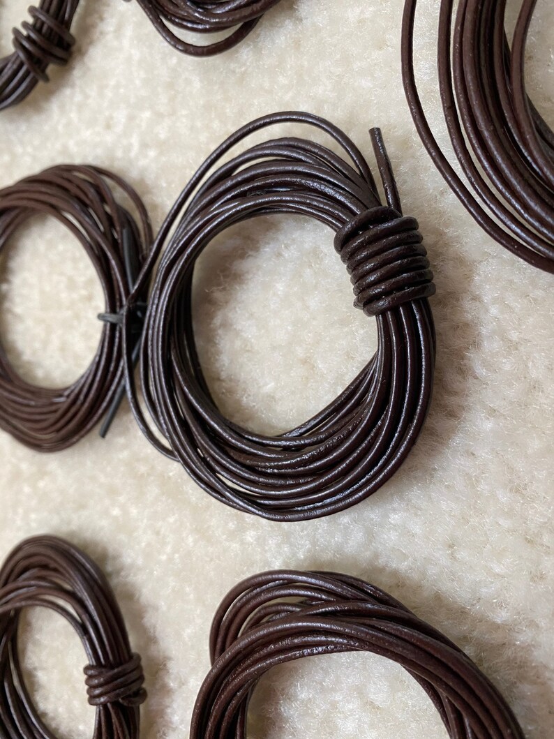 May include: Close-up of five spools of brown leather cord. The cord is wound into neat circles and is ready for crafting projects.