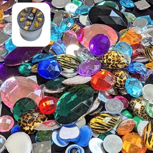 Puede incluir: Un gran surtido de adornos decorativos de colores, que incluyen piedras de imitaci&oacute;n, gemas de vidrio y cuentas de pl&aacute;stico. Los adornos son de varias formas y tama&ntilde;os, incluyendo redondos, ovalados y en forma de coraz&oacute;n. Los colores incluyen rojo, azul, verde, morado, rosa y transparente.