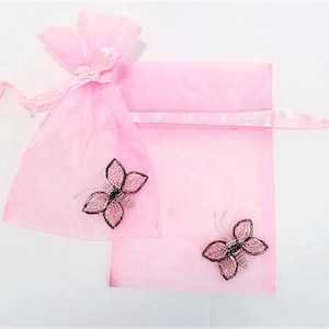May include: Two pink organza bags with a satin ribbon tie. Each bag features a beaded butterfly embellishment.