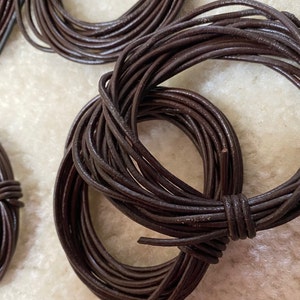May include: A close-up of a spool of brown leather cord. The cord is wound tightly and is ready to be used for crafting projects.