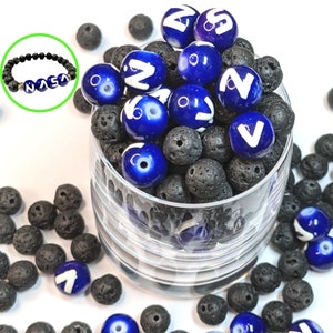 May include: A close-up of a glass jar filled with blue and black beads. The blue beads have white letters on them, spelling out the word "Nava." The black beads are small and round. There are also some blue and black beads scattered around the jar.