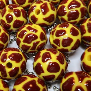 May include: A collection of yellow and brown patterned beads. The beads are round and have a hole in the center. The beads are made of a glossy material.