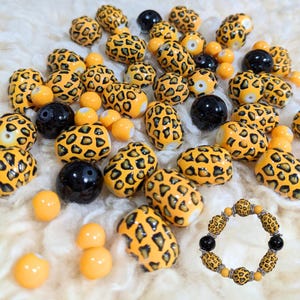 May include: A collection of yellow and black leopard print beads with a matching bracelet. The beads are oval shaped and have a glossy finish.