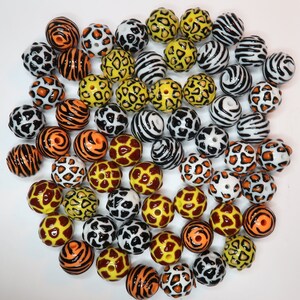 May include: A collection of colourful round beads with various animal print patterns, including zebra, leopard, and giraffe. The beads are made of plastic and are ideal for crafting projects.