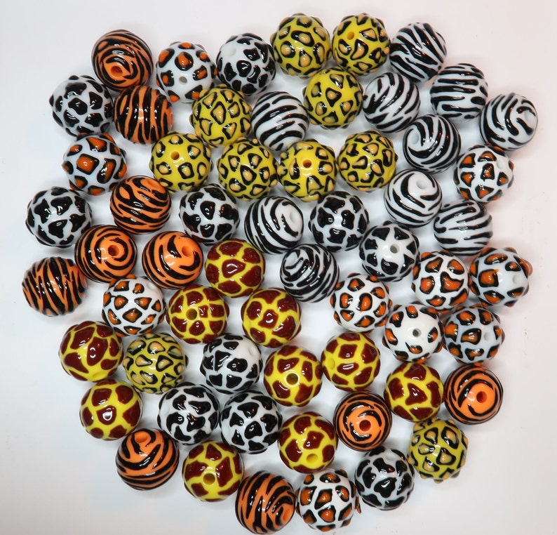 May include: A collection of colourful round beads with various animal print patterns, including zebra, leopard, and giraffe. The beads are made of plastic and are ideal for crafting projects.