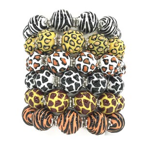 May include: A stack of six colourful bracelets featuring various animal print designs. The bracelets are made from round beads with a glossy finish. The designs include zebra, leopard, and giraffe prints.
