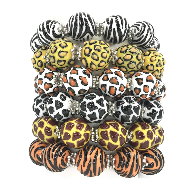 May include: A stack of six colourful bracelets featuring various animal print designs. The bracelets are made from round beads with a glossy finish. The designs include zebra, leopard, and giraffe prints.