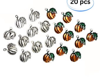 May include: A collection of 20 pumpkin charms, featuring a mix of silver-toned metal and orange-enameled pumpkins with green leaves. Each small charm includes a loop at the top for attachment, displaying detailed ridges and stems.