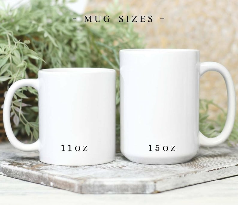 May include: Two white ceramic mugs with handles, displayed side by side. The smaller mug is labeled 11oz and the larger mug is labeled 15oz. The text MUG SIZES is centered above the mugs. The mugs have a smooth, glossy finish and a cylindrical shape.