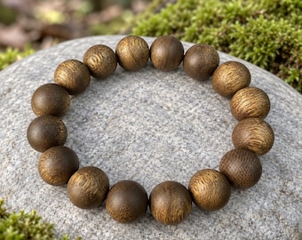 May include: A circular bracelet composed of sixteen spherical wooden beads. Each bead features a distinct, natural brown grain pattern with golden-brown highlights, arranged in a continuous loop to form a uniform, polished, and rounded accessory.