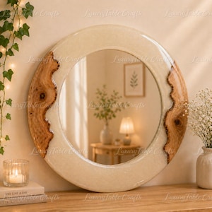 May include: Circular wall mirror featuring a cream resin frame with sections of natural wood. The mirror reflects a room with a lamp and artwork. A decorative item for home interiors.
