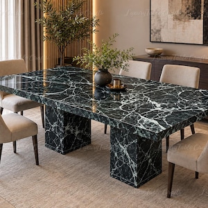 Peut inclure: Une table à manger rectangulaire dotée d'une surface en marbre vert foncé poli avec des veines blanches marquées, reposant sur deux pieds piédestaux épais en marbre assorti, entourée de six chaises rembourrées aux pieds en bois sombre.