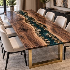 May include: A rectangular dining table featuring a live-edge walnut wood top with a central river design filled with translucent blue resin and embedded smooth river stones. The table is supported by a brushed gold metal U-shaped base.