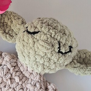 Pu&ograve; includere: Un giocattolo di peluche verde all'uncinetto con un viso sorridente e grandi orecchie. Il giocattolo &egrave; fatto di filato morbido e testurizzato e ha un corpo marrone chiaro.
