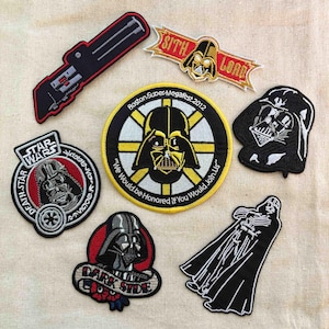 May include: A collection of Star Wars themed embroidered patches. Designs include Darth Vader, a lightsaber, and text such as "Sith Lord", "Star Wars", and "Dark Side". One patch is a Boston Super Megafest 2012 commemorative.