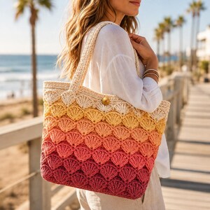 May include: A crochet tote bag featuring a scalloped shell pattern in an ombre gradient of colors, transitioning from cream at the top to yellow, peach, coral, and deep pink at the base, finished with a single wooden button closure at the center.