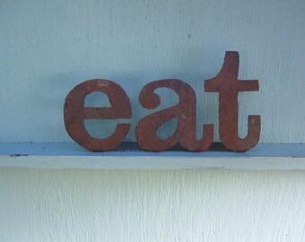 Metal "eat" sign on stand. Great for a rustic or modern kitchen. A fun decor piece for your cook from Screaming Horse Iron Works.