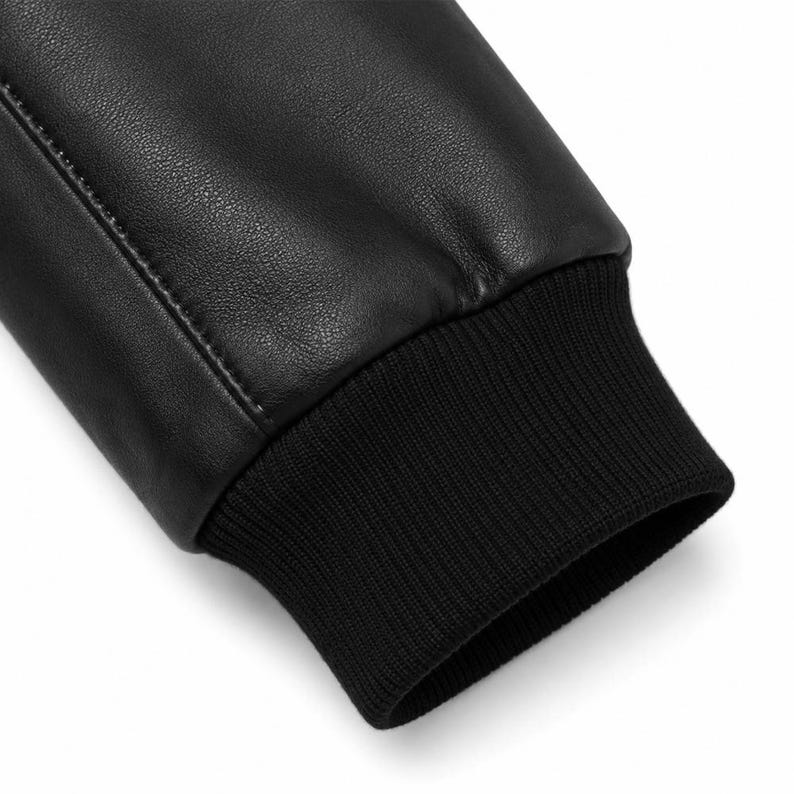 Black leather bomber jacket for men with faux fur collar, front zipper closure, ribbed cuffs, and classic aviator style design on white background.