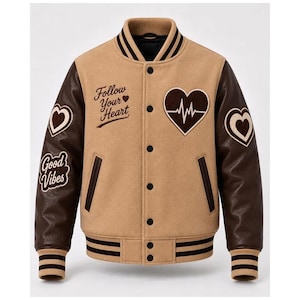May include: A tan varsity jacket with dark brown sleeves, featuring a front button closure and striped ribbed trim. The chest displays the text Follow Your Heart and a heart-shaped EKG graphic, while the sleeves feature heart and Good Vibes patches.