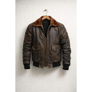 Men wearing distressed brown leather bomber jacket with fur collar and vintage aviator style.