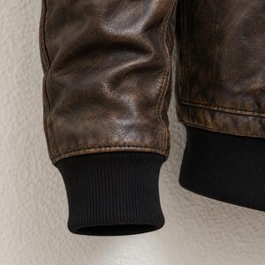 Men wearing distressed brown leather bomber jacket with fur collar and vintage aviator style.