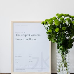 Puede incluir: Un cartel enmarcado con el texto "WATER ZHI The deepest wisdom flows in stillness". Un jarrón de cristal transparente con diseño de burbujas contiene flores verdes. El cartel está en un marco de madera clara.