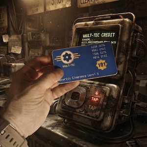 May include: A blue Vault-Tec credit card featuring a yellow gear logo, the number 101, and the text Security Clearance Level 5. The card displays a sequence of numbers and is held in front of a metallic, weathered terminal with a glowing green screen.