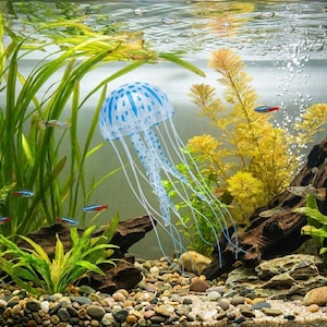 Pu&ograve; includere: Scena di acquario con una decorazione di medusa a pois blu e bianchi con lunghi tentacoli fluttuanti. La vasca include piante vive, piccoli pesci e un substrato di ghiaia, creando un ambiente sottomarino vibrante.