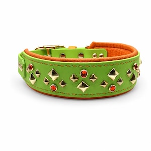 May include: A lime green leather collar featuring a bright orange interior lining. The exterior is decorated with gold-toned pyramid studs and small, round, orange-red gemstones arranged in a repeating pattern along the length of the band.