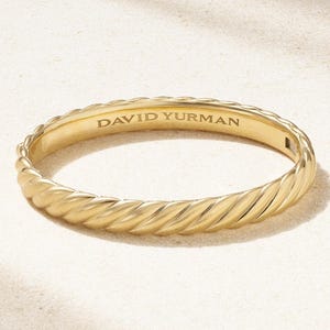 Può includere: Un bracciale rigido in oro caratterizzato da una texture intrecciata simile a una corda lungo tutta la fascia. L'interno del bracciale è liscio e riporta l'incisione del marchio DAVID YURMAN in lettere maiuscole sulla superficie interna.