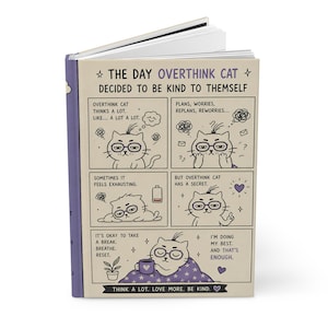 May include: A hardback journal with a purple spine and a comic strip design. The cover features a cat character with glasses and text that reads "The Day Overthink Cat Decided to Be Kind to Themself." The journal's theme is self-care and mental wellbeing.