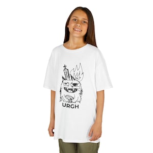 May include: White t-shirt featuring a black and white cartoon monster design with the word "URGH" printed below. The monster has a crown and flames. The shirt is worn by a person.
