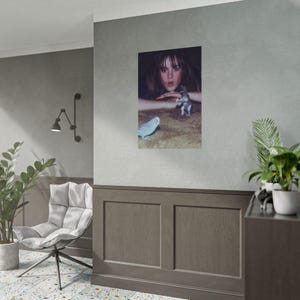 a cozy living room with a gray wall, a framed photograph of a woman with a cat, a potted plant, and a chair.