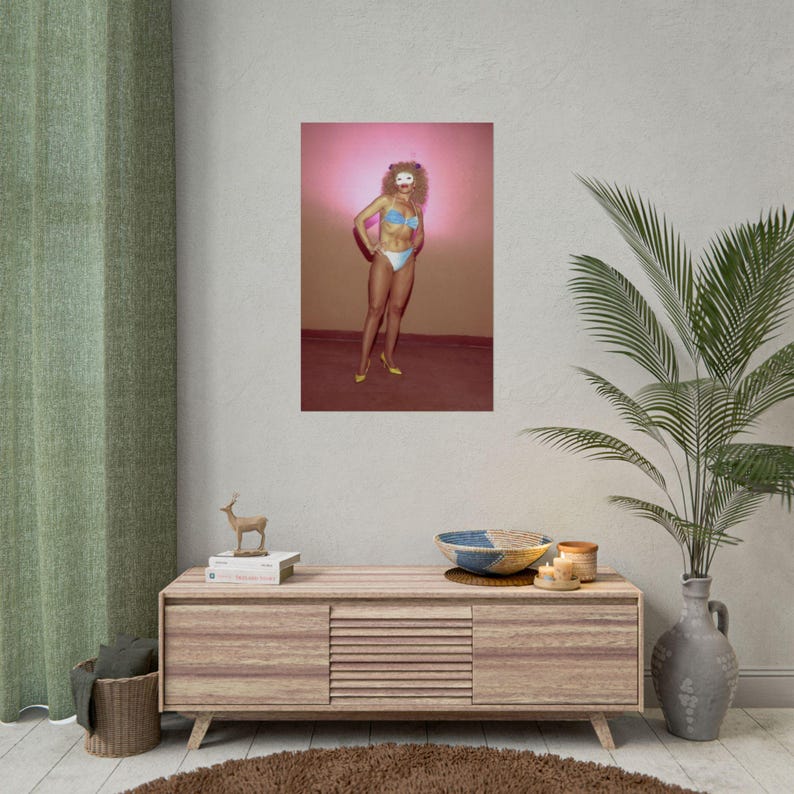a poster of a woman in a bikini, displayed on a wall above a wooden entertainment center with various decorative items.