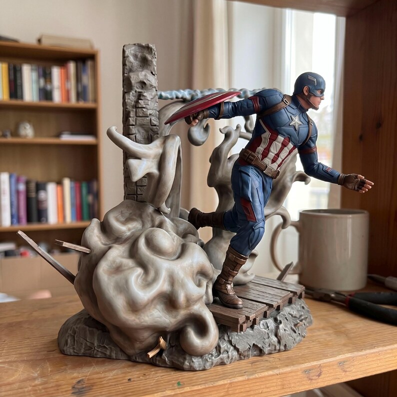 May include: A Captain America action figure in a dynamic running pose, wearing a blue, red, and white suit with a star emblem. The figure holds a circular red, white, and blue shield, mounted on a base featuring a stone pillar and smoke effects.