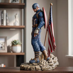 May include: A detailed figurine of a superhero wearing a blue tactical suit, a helmet with an 'A' emblem, and brown boots. The figure carries a round red, white, and blue shield on its back and stands next to a tall American flag on a rocky base.
