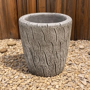 May include: A cylindrical planter with a textured grey exterior that mimics the appearance of tree bark. The surface features vertical, curved indentations throughout, creating a rugged, organic look. The interior is smooth and hollow.