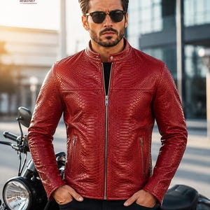 May include: A red leather jacket with a textured snakeskin pattern, a stand-up collar with a snap button, and a full-length silver front zipper. The jacket features two side pockets with silver zippers and long sleeves. The logo ALVERA leather is visible.