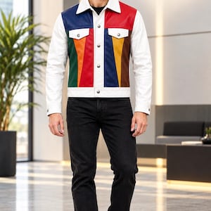 Puede incluir: Una chaqueta de cuero multicolor con cuello, mangas y dobladillo blancos, con paneles verticales en rojo, azul, verde, amarillo y marrón en la parte delantera. La chaqueta incluye botones metálicos plateados y dos bolsillos en el pecho con solapas.