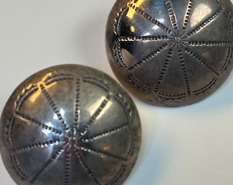 May include: A pair of silver earrings with a circular design. The earrings have a textured surface and a raised center.