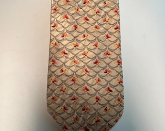 May include: A beige silk tie with a repeating pattern of small red and orange flowers. The flowers are arranged in a wave-like pattern.