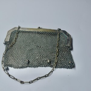 May include: A vintage silver mesh purse with a chain handle. The purse has a rectangular shape with a metal frame and a delicate chain strap. The mesh is finely woven, and the purse appears to be in good condition.