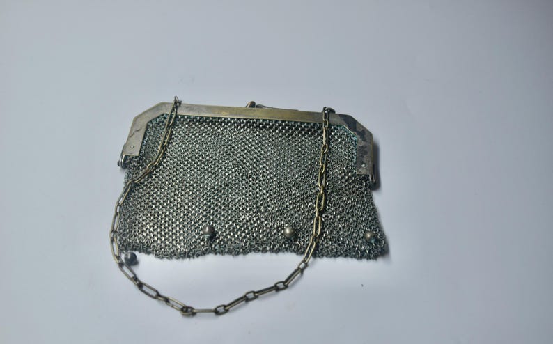 May include: A vintage silver mesh purse with a chain handle. The purse has a rectangular shape with a metal frame and a delicate chain strap. The mesh is finely woven, and the purse appears to be in good condition.