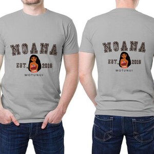 Pu&ograve; includere: T-shirt grigie chiare con la scritta "MOANA" in marrone, con un carattere in stile collegiale. La parte anteriore della maglietta presenta un'immagine a cartoni animati di Moana, la scritta "EST. 2016" e "MOTUNUI". Il retro della maglietta ha lo stesso design.