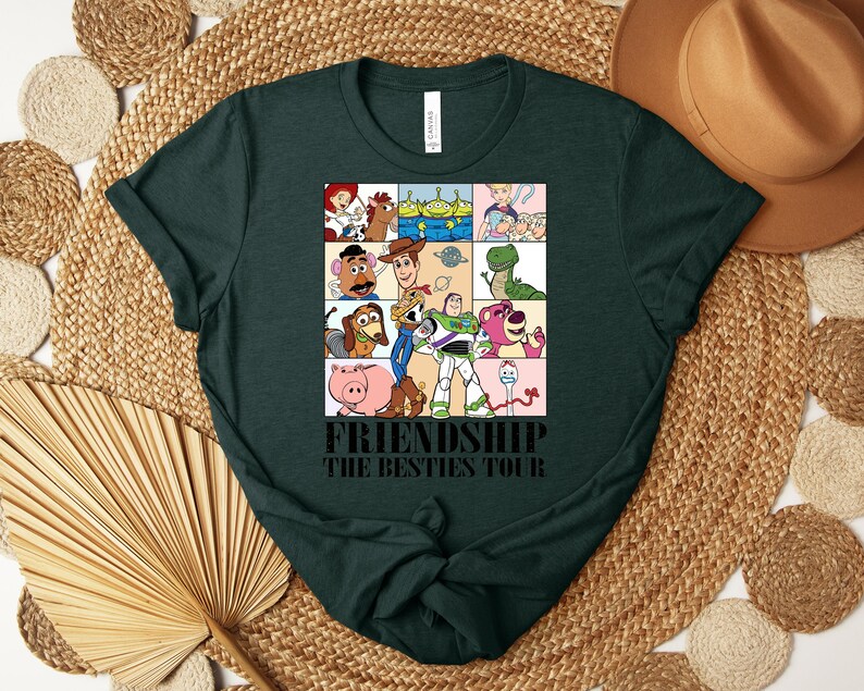 Puede incluir: Camiseta verde oscuro con un gr&aacute;fico colorido de personajes de dibujos animados en una cuadr&iacute;cula. El texto "FRIENDSHIP THE BESTIES TOUR" est&aacute; impreso debajo. La camiseta est&aacute; hecha de un material suave. Una prenda casual para el d&iacute;a a d&iacute;a.